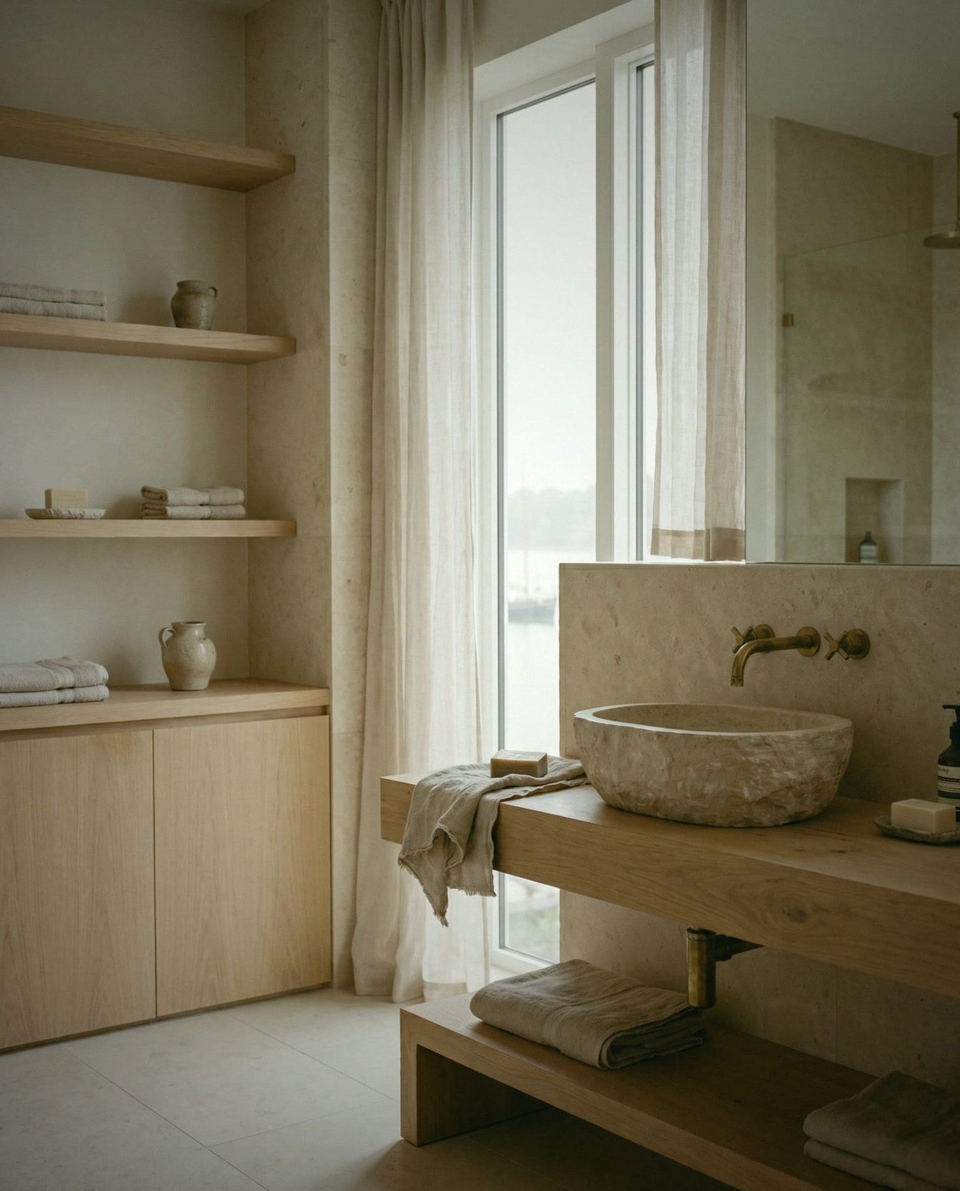 Salle de bain en pierre claire et chêne, vasque en pierre, robinetterie laiton.