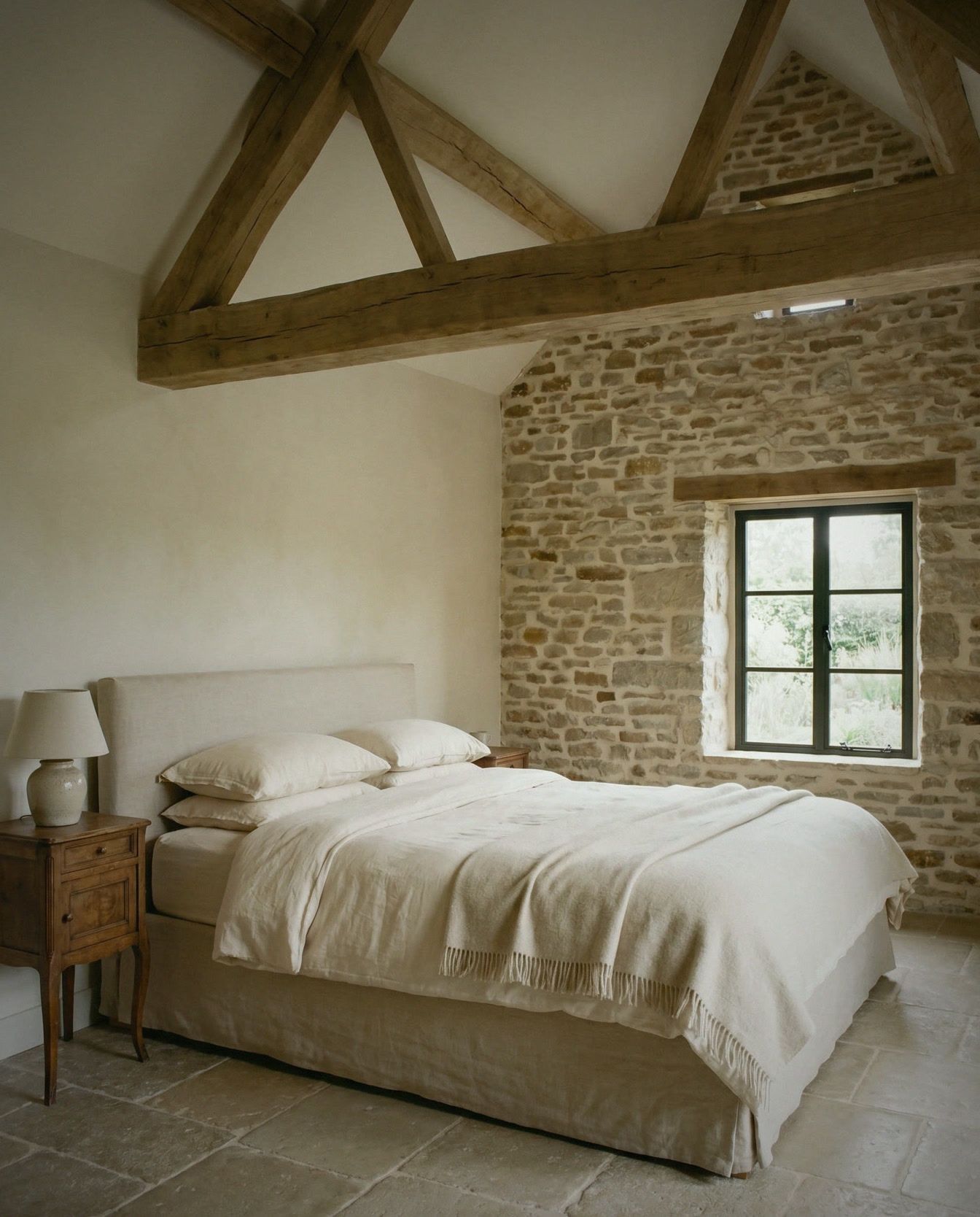 Chambre sous charpente chêne, lit en lin, plâtre et pierre apparente.